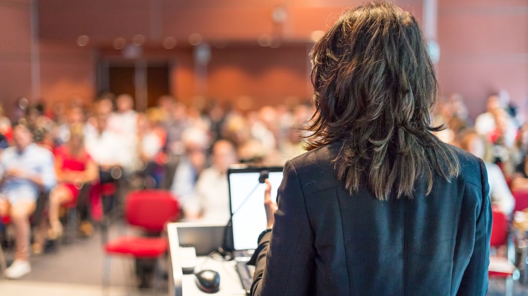 Female Public Speaker Giving Talk at Business Event.